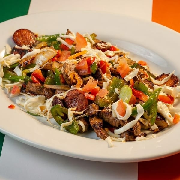 A white oval plate filled with a colorful stir-fry of meat, peppers, and cabbage.