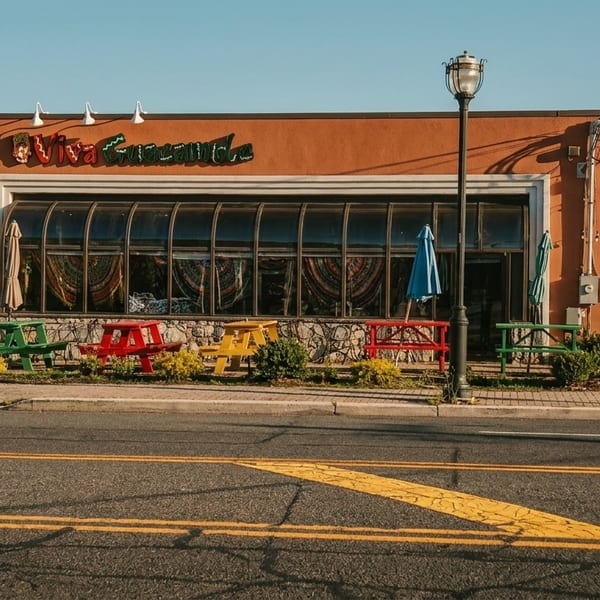 Viva Guacamole restaurant exterior with colorful picnic tables and a large curved window facade.